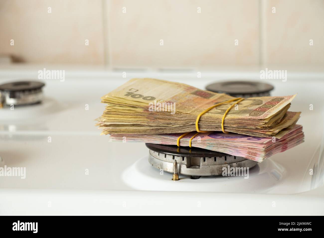 One hundred and two hundred hryvnia lie on a gas stove in the kitchen, Ukrainian hryvnia and gas, finance and economics, money and sanctions Stock Photo