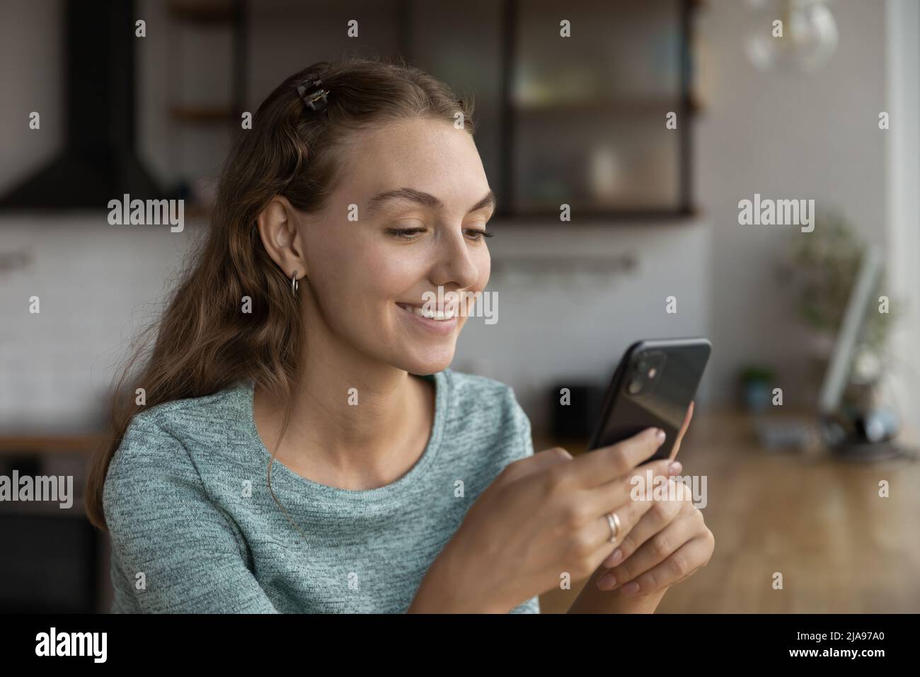 Happy beautiful gen Z teen girl chatting on smartphone online Stock Photo