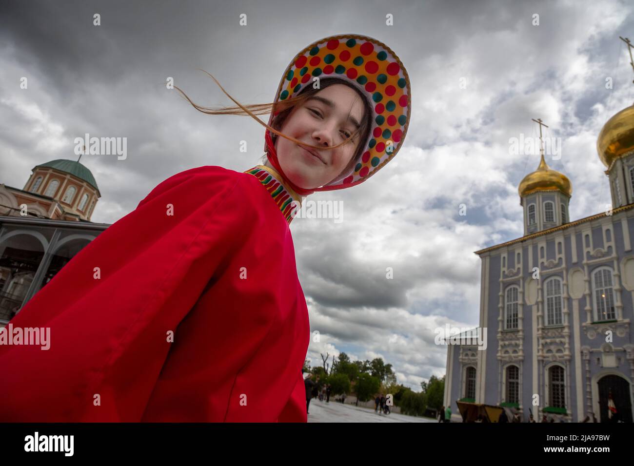 Tula, Russia. 28th May, 2022. A girl in a costume stylized as a Filimonov clay toy walks along a terrytory of the Kremlin in background of the ancient Assumption Cathedral in the center of Tula town, Russia Stock Photo
