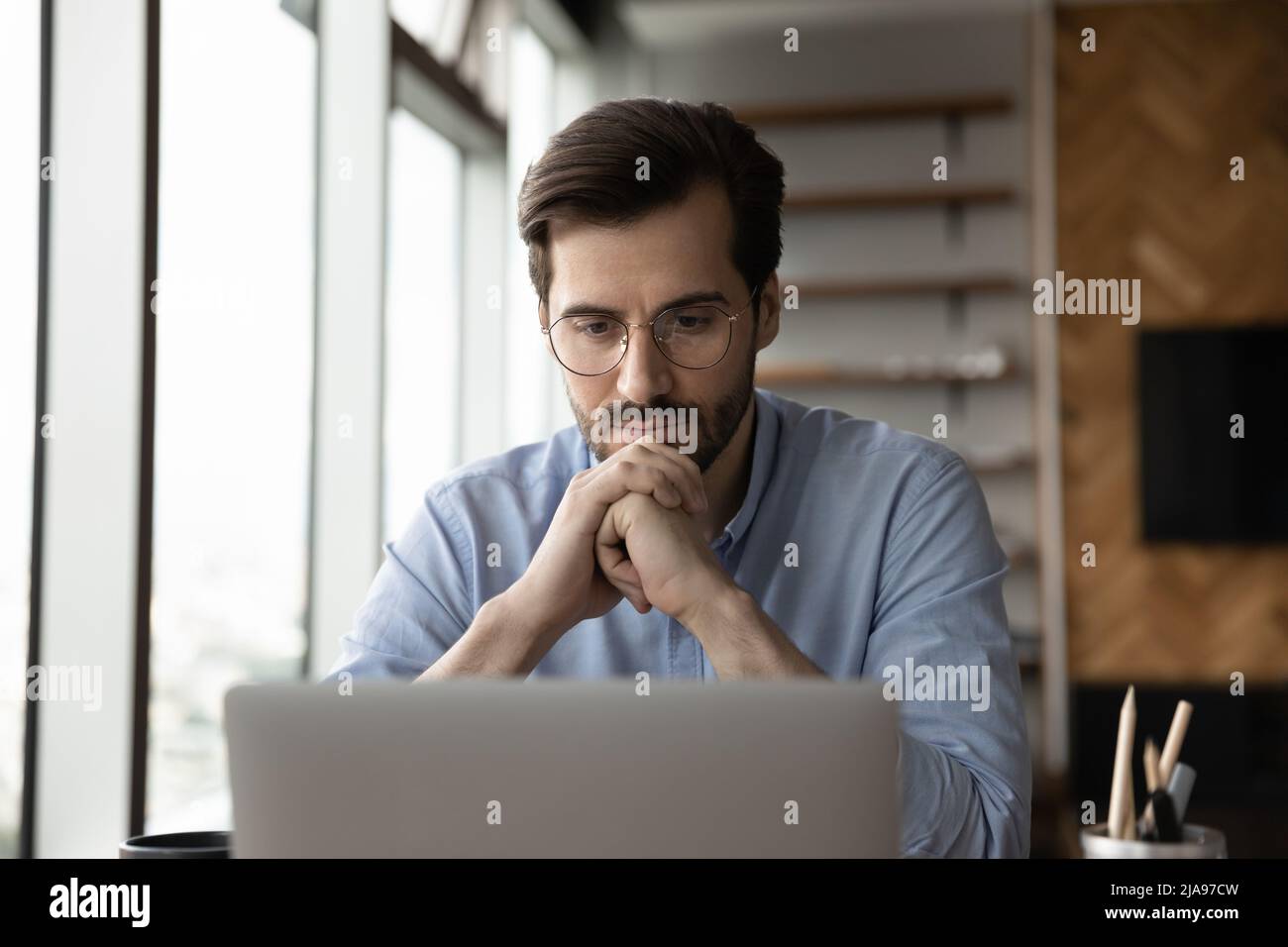 Thoughtful focused business man in glasses working at laptop computer Stock Photo