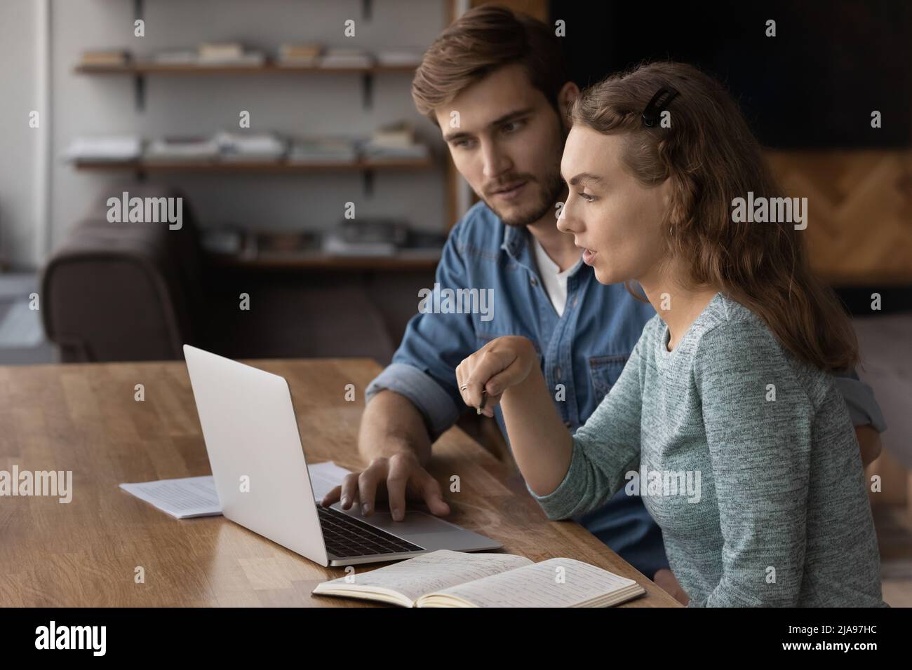 Two focused students discussing learning task at laptop Stock Photo
