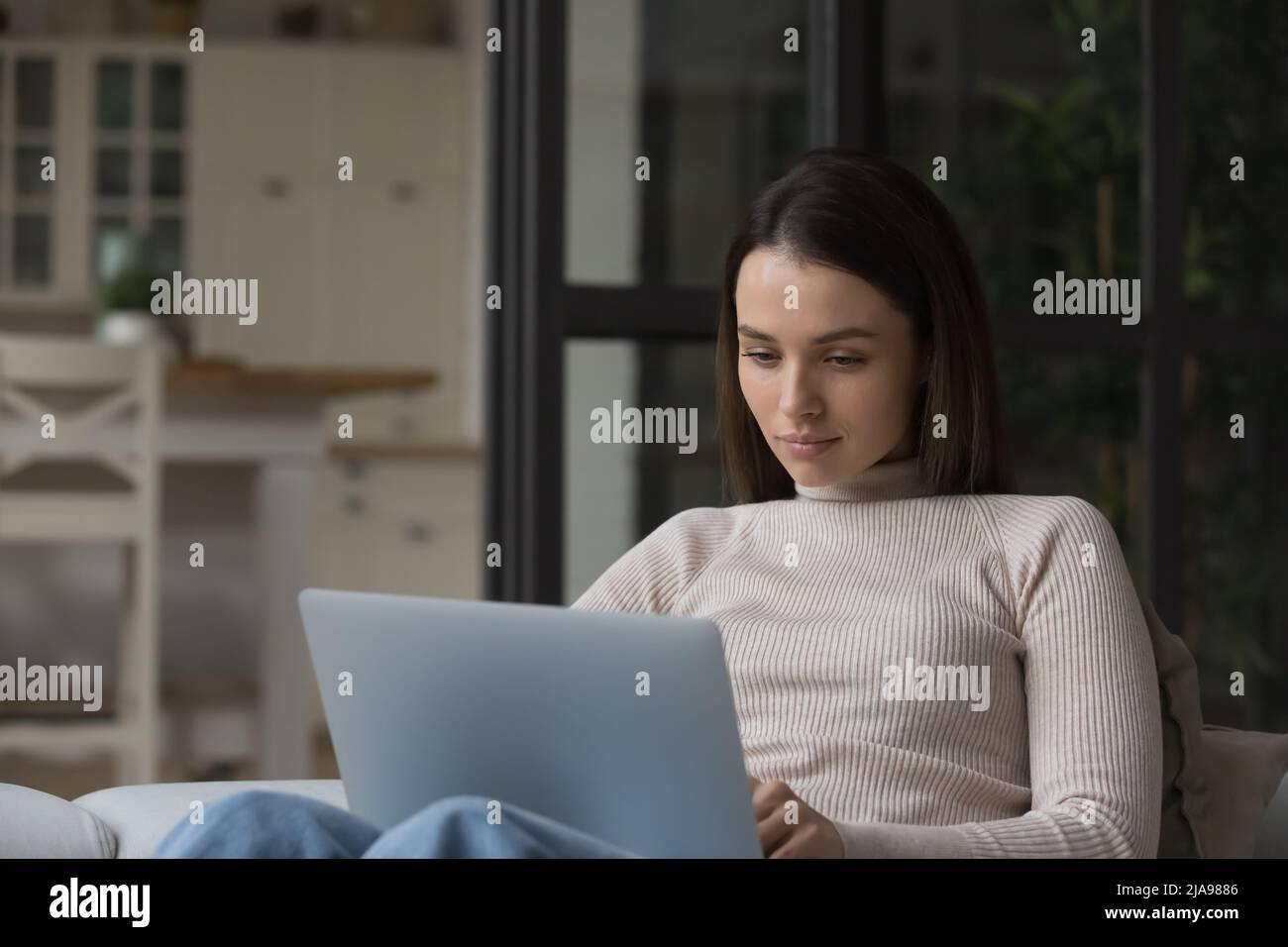 Serious pensive freelance employee woman using laptop Stock Photo