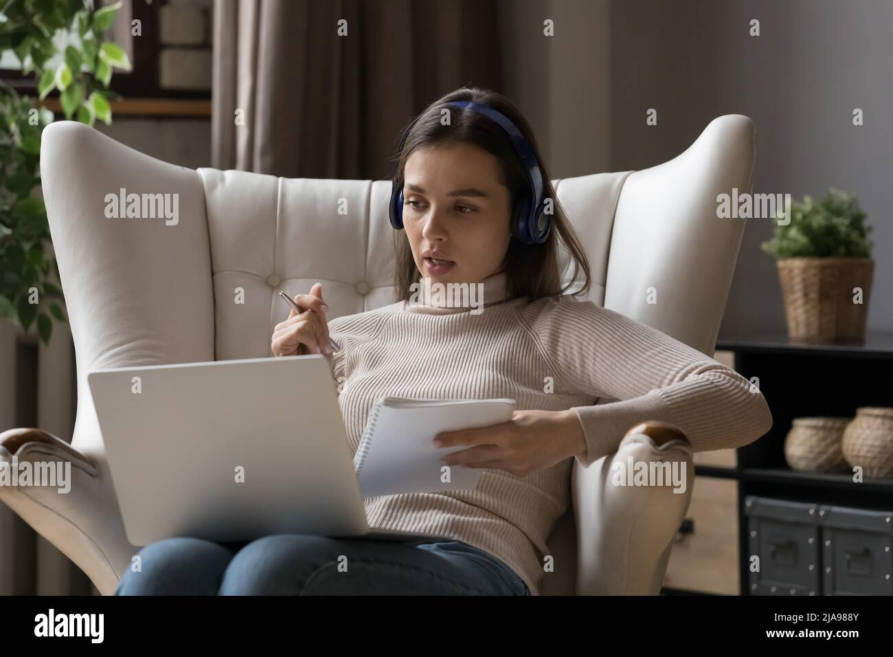 Serious millennial student girl in wireless headphones talking to ...