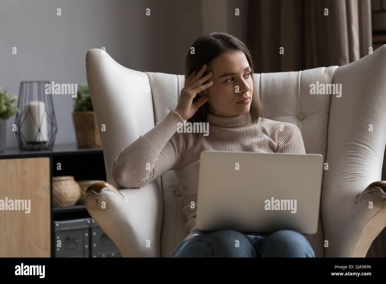 Thoughtful pretty young freelance business woman working at laptop Stock Photo
