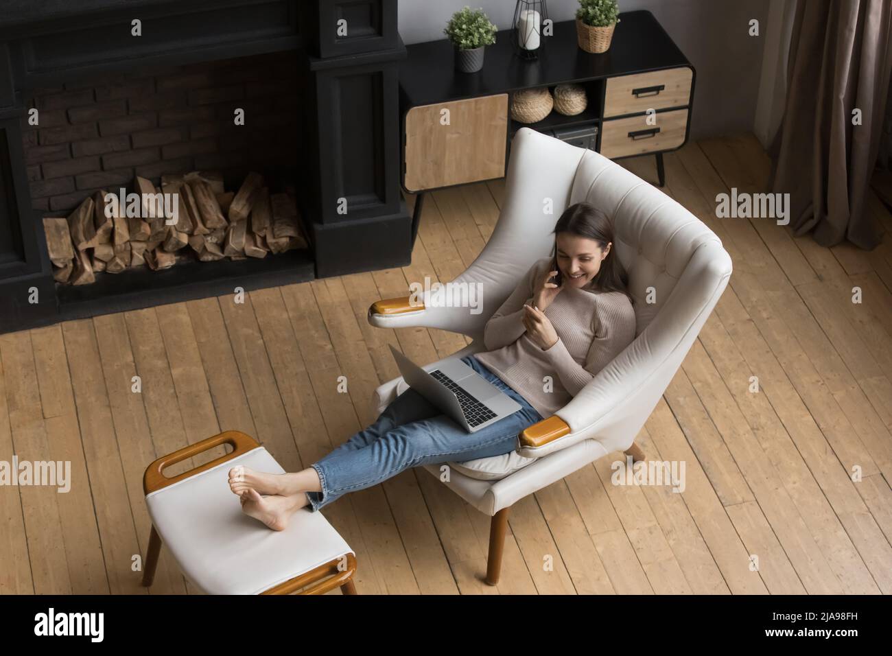 Happy freelance employee woman talking on mobile phone at home Stock Photo