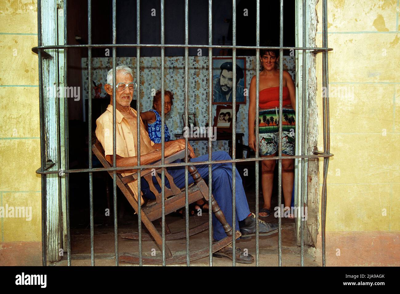 Old man in a rocking chair behind a barred window, old town of Trinidad, Unesco World Heritage Site, Cuba, Caribbean Stock Photo