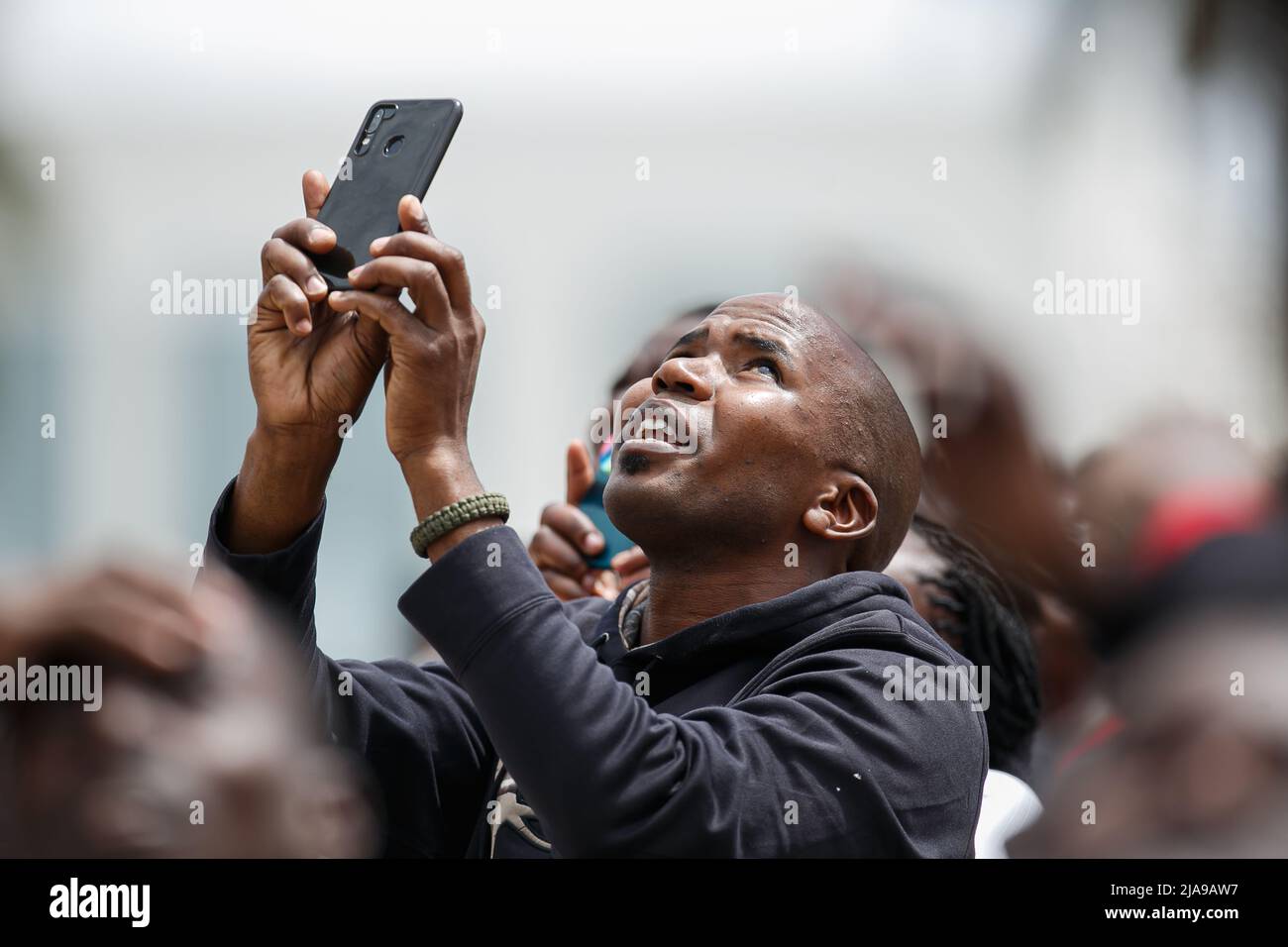 Nairobi, Kenya. 28th May, 2022. A Kenyan man video records with his phone the happenings of the day at the Kenya Defence Forces Air Show at the Uhuru Gardens National Monument and Museum. The free Air Show was a forerunner of commissioning the Uhuru Gardens National Monument and Museum. It was led by Kenya Air Force and included the Kenya wildlife services and civilian aerobatic and sky diving teams. The aim was to entertain and educate the public. Credit: SOPA Images Limited/Alamy Live News Stock Photo
