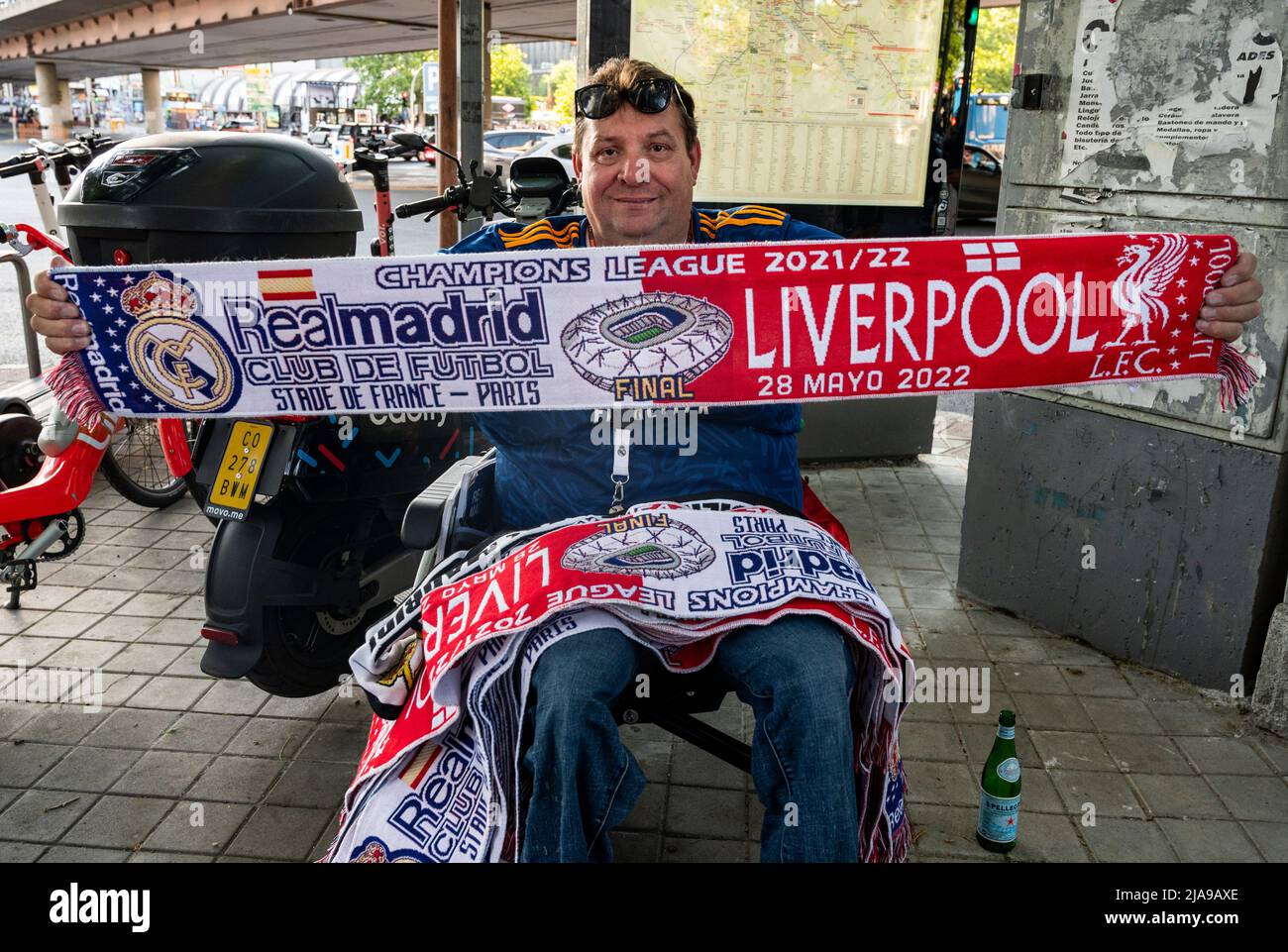 Madrid, Spain. 29th May, 2022. A stall vendor poses with a scarf  commemorating the 2022 UEFA Champions League final match between Liverpool  and Real Madrid in Madrid. Real Madrid won its 14th