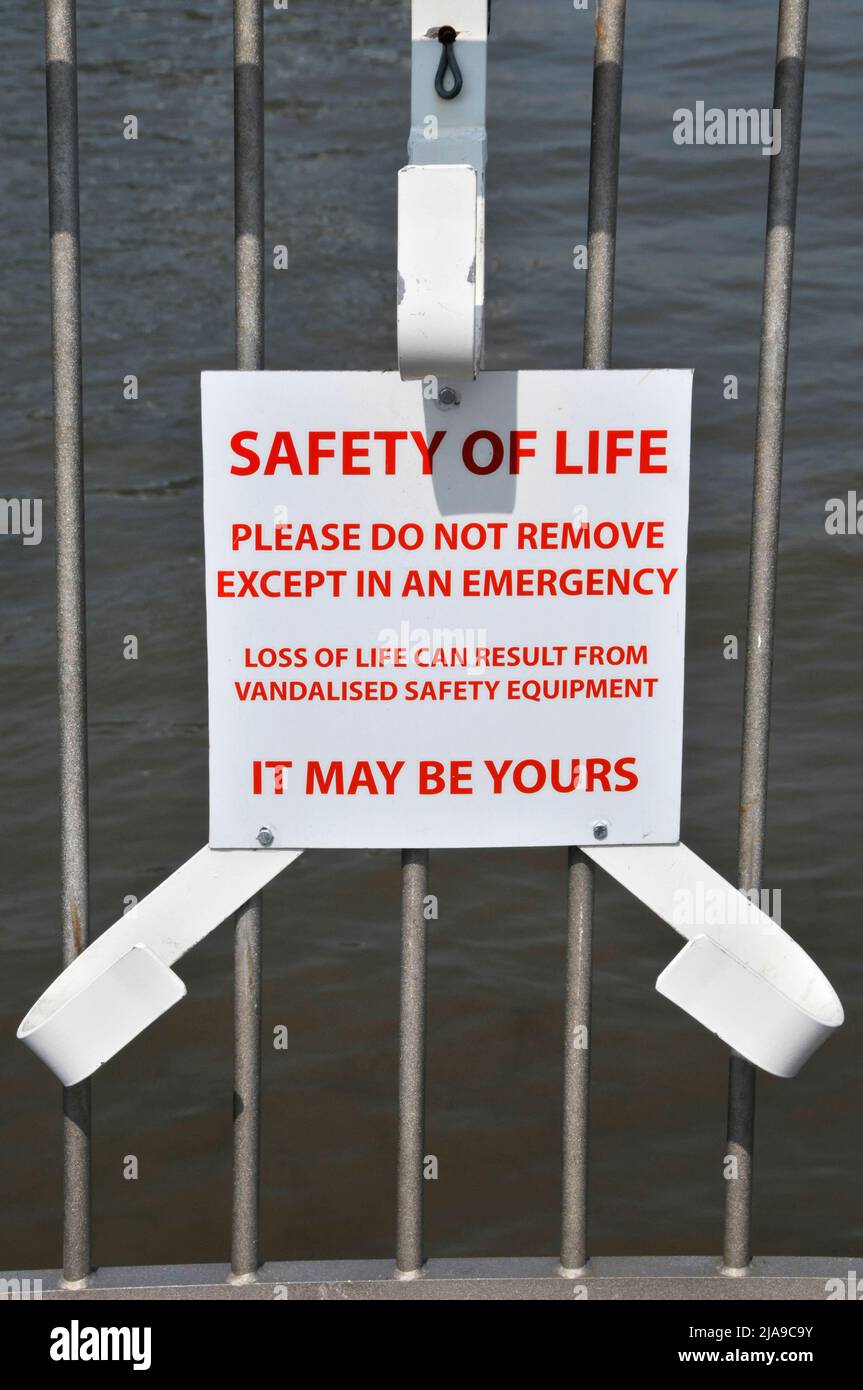 Riverside lifebuoy ring missing from support bracket exposing safety message warning of risk to life that vandalism can cause when removed England UK Stock Photo