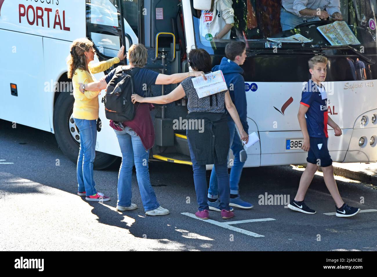 Teachers & minders link arms for pupil protection safe exit left hand drive French coach in roadside parking bay Park Lane Hyde Park London England UK Stock Photo