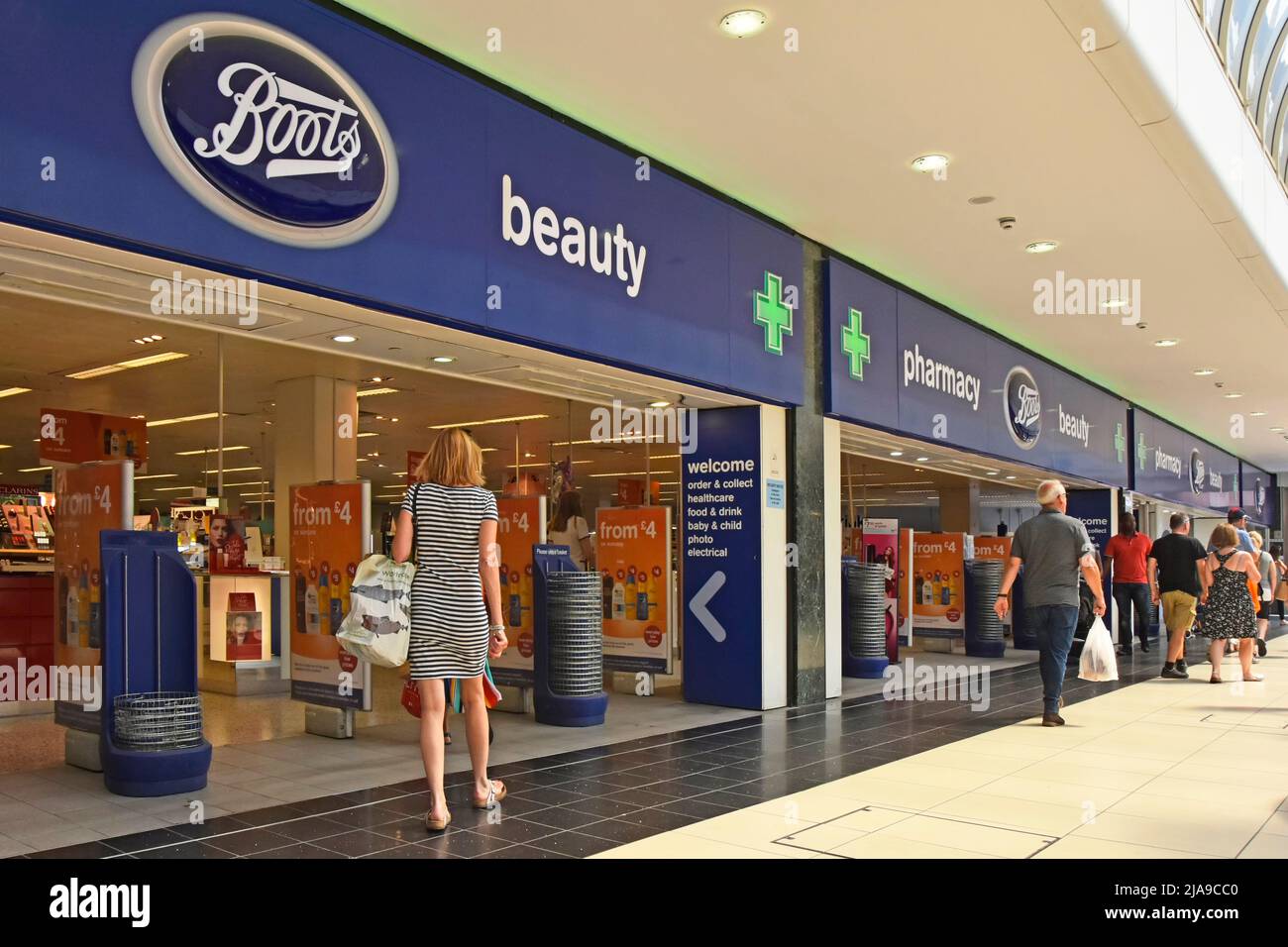 Green Pharmacy Cross signs above entrances to Boots chemist retail shop business & beauty store shoppers in shopping centre mall Chelmsford England UK Stock Photo