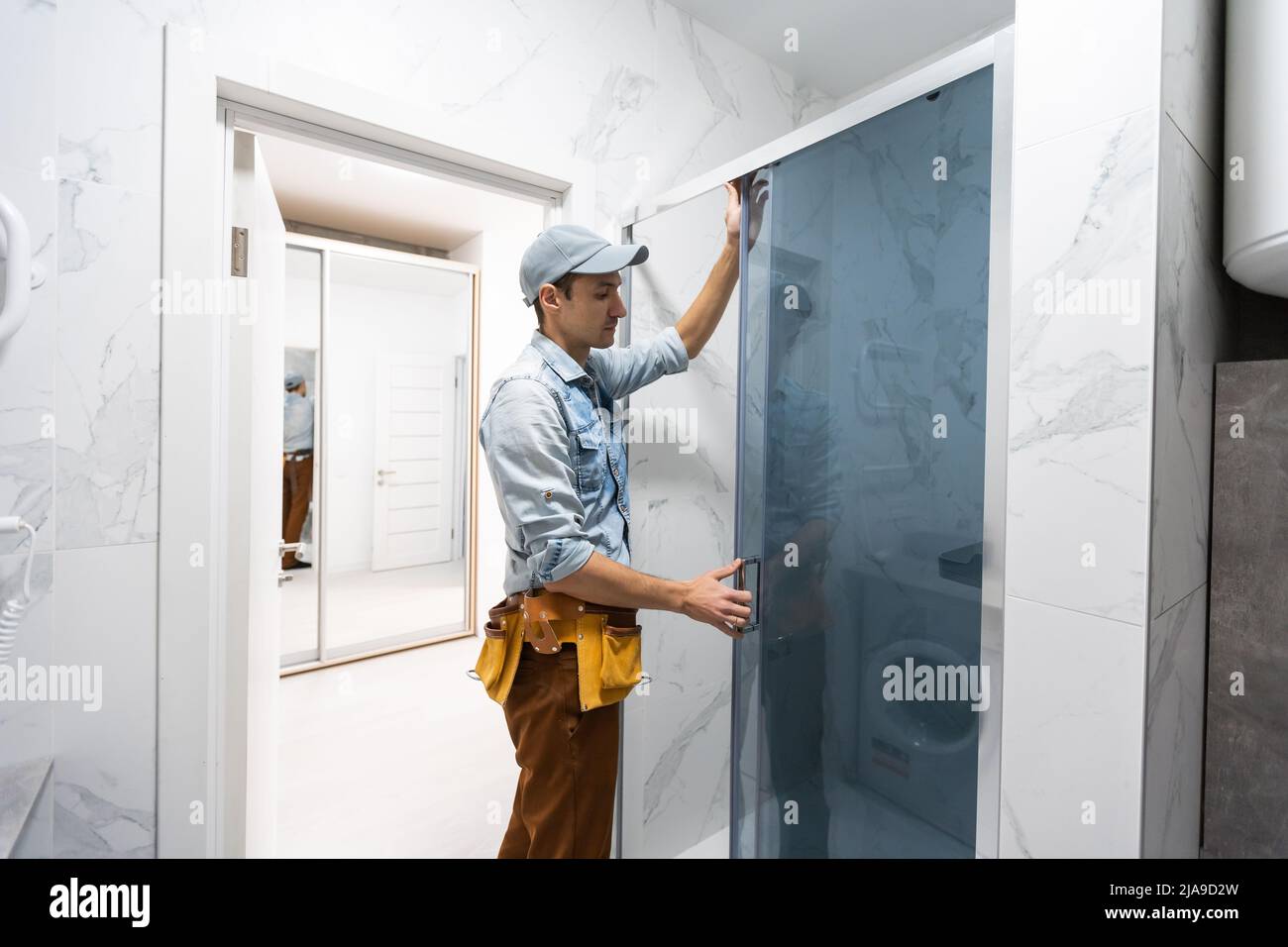 Handyman installing glass in bathroom Stock Photo Alamy