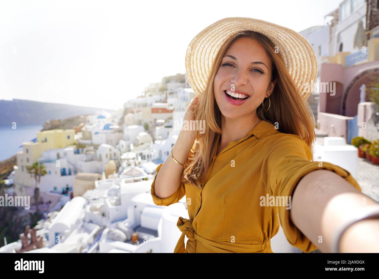 Hispanic exuberant fashion woman having fun taking self portrait on sunset in Santorini Island, Greece Stock Photo