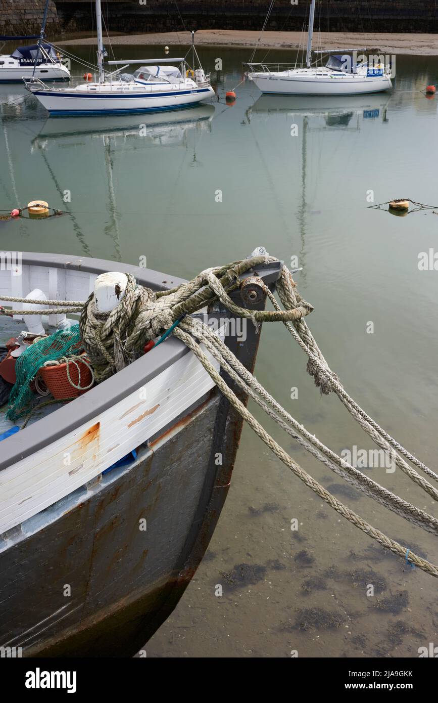 Bow of wooden fishing boat with rope mooring lines, and sailing yachts