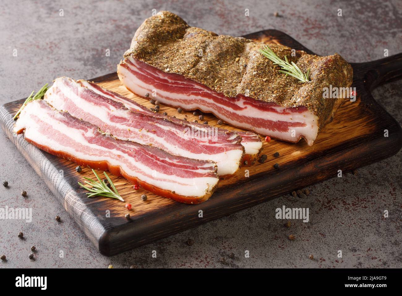 https://c8.alamy.com/comp/2JA9GT9/pancetta-italian-is-a-salt-cured-pork-belly-salume-closeup-on-the-wooden-board-on-the-table-horizontal-2JA9GT9.jpg