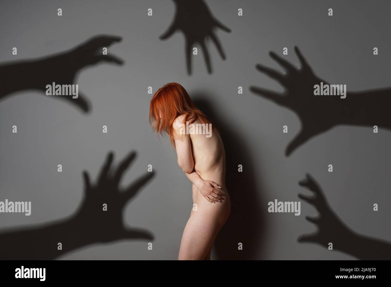 sexual harassment or abuse concept with naked woman shadows of grabbing hands Stock Photo