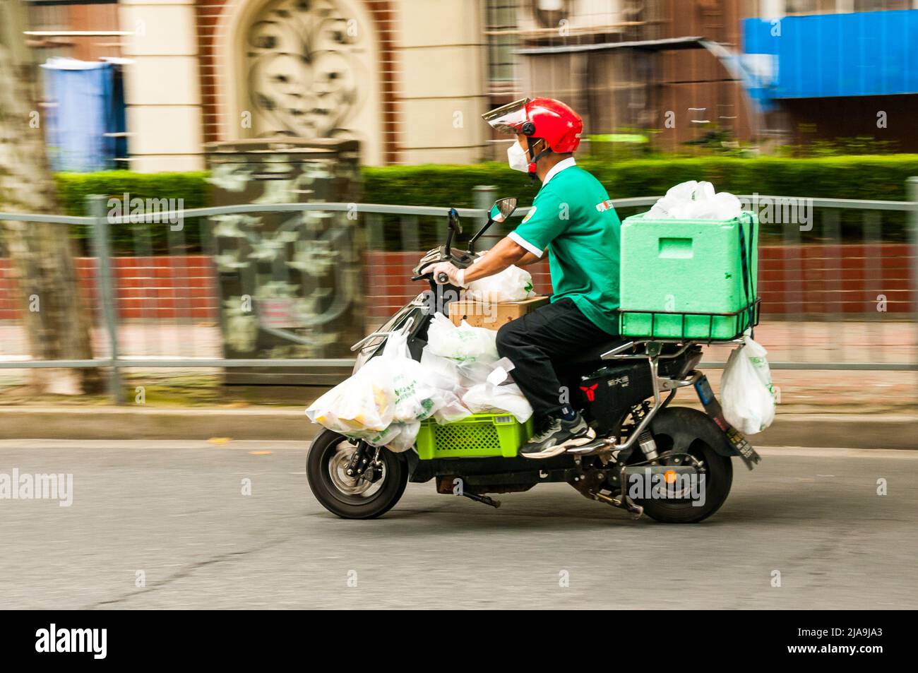 A delivery rider from the Dingdong Maicai app delivering groceries in Putuo District, Shanghai, China during the end of Shanghai’s lockdown. Stock Photo