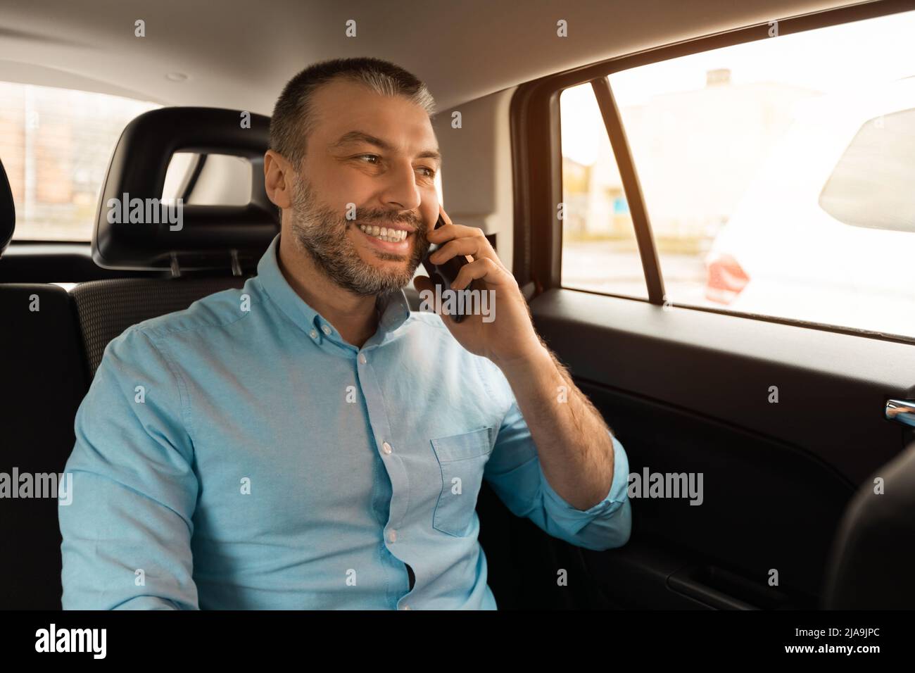 Businessman talking on smartphone while going by car Stock Photo
