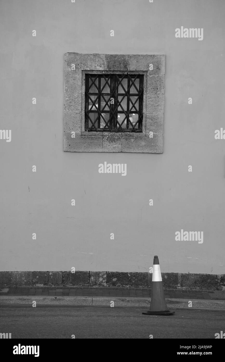 Wooden antique windows with square shape on a painted old wall and Traffic Cone. Black and white Stock Photo