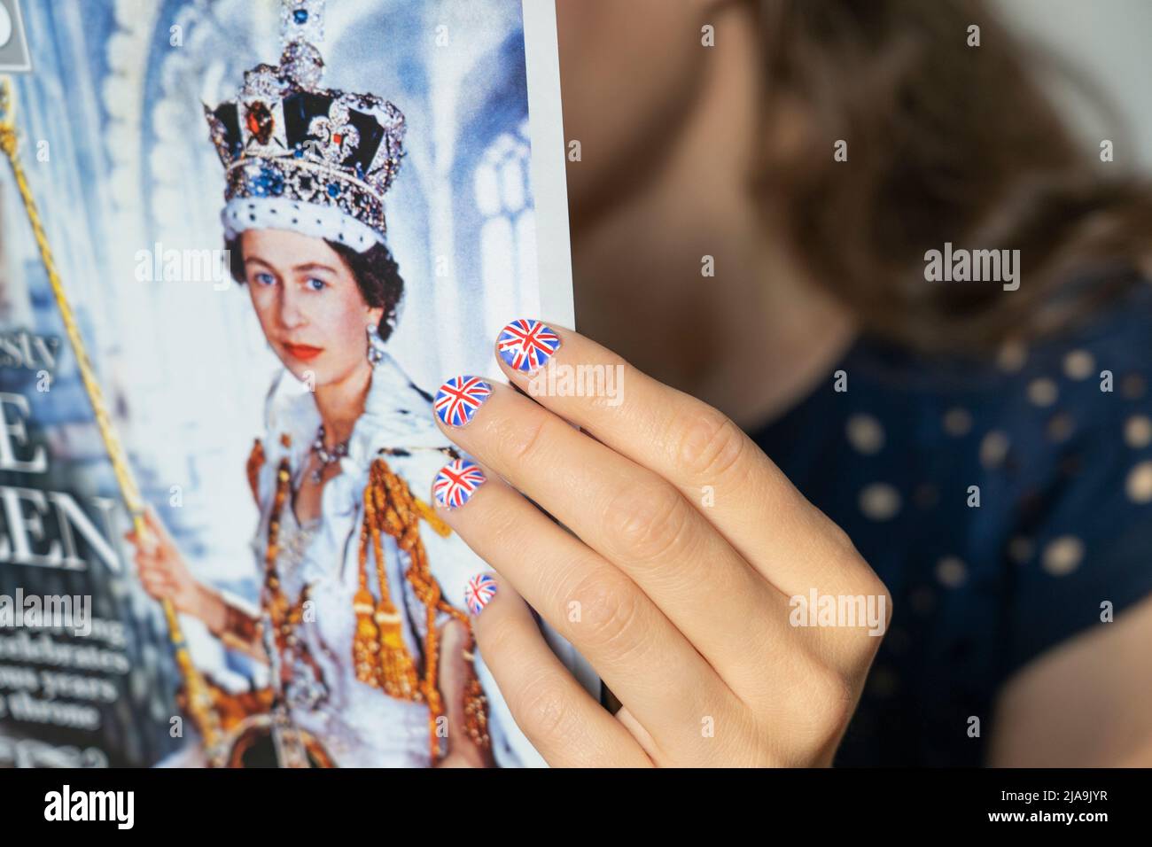 Fan with fingernails painted with the British Flag holding a copy of OK magazine with a picture of the Queen's Coronation. Platinum Jubilee June 2022 Stock Photo