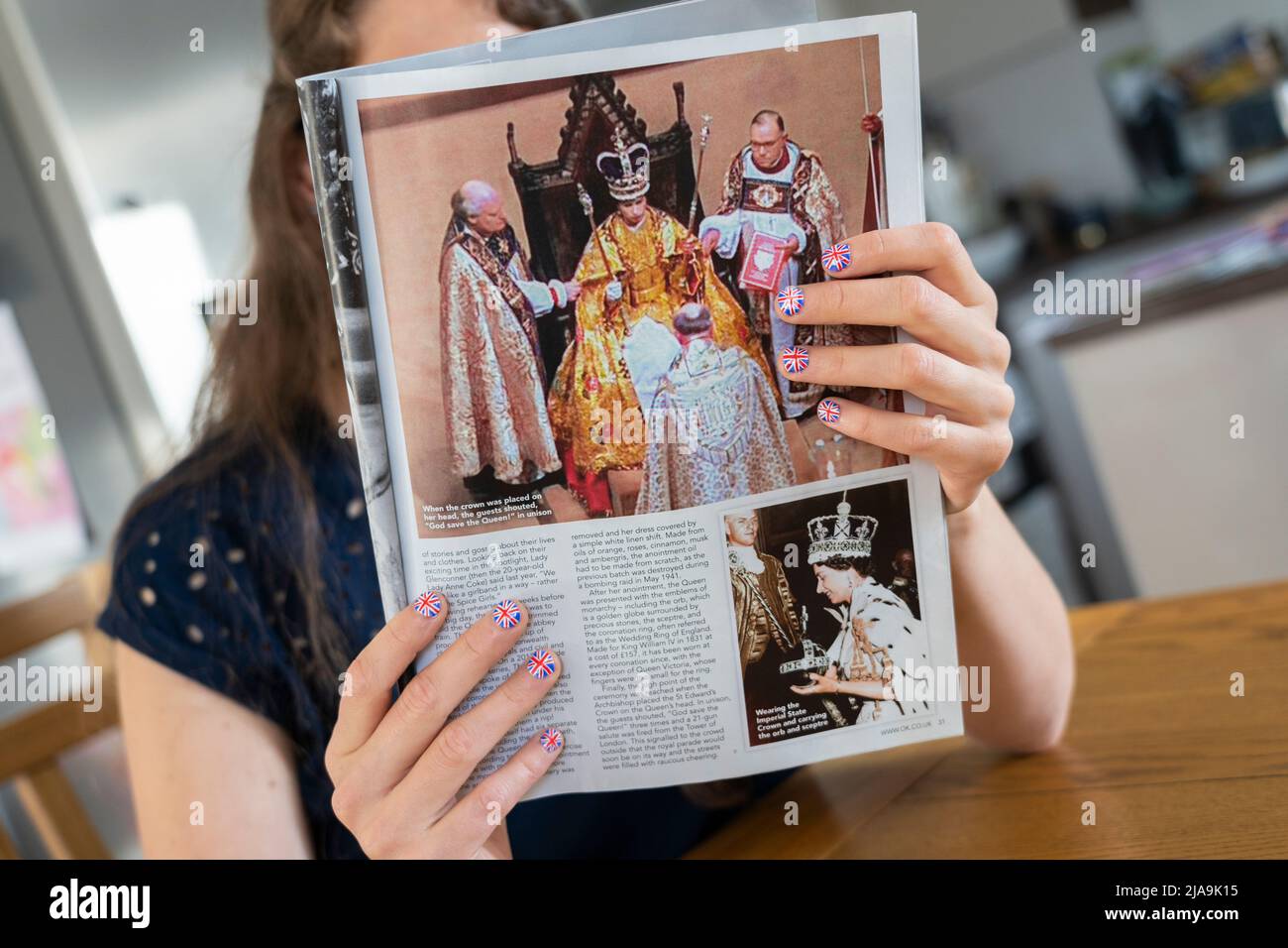 Fan with fingernails painted with the British Flag holding a copy of OK magazine with a picture of the Queen's Coronation. Platinum Jubilee June 2022 Stock Photo