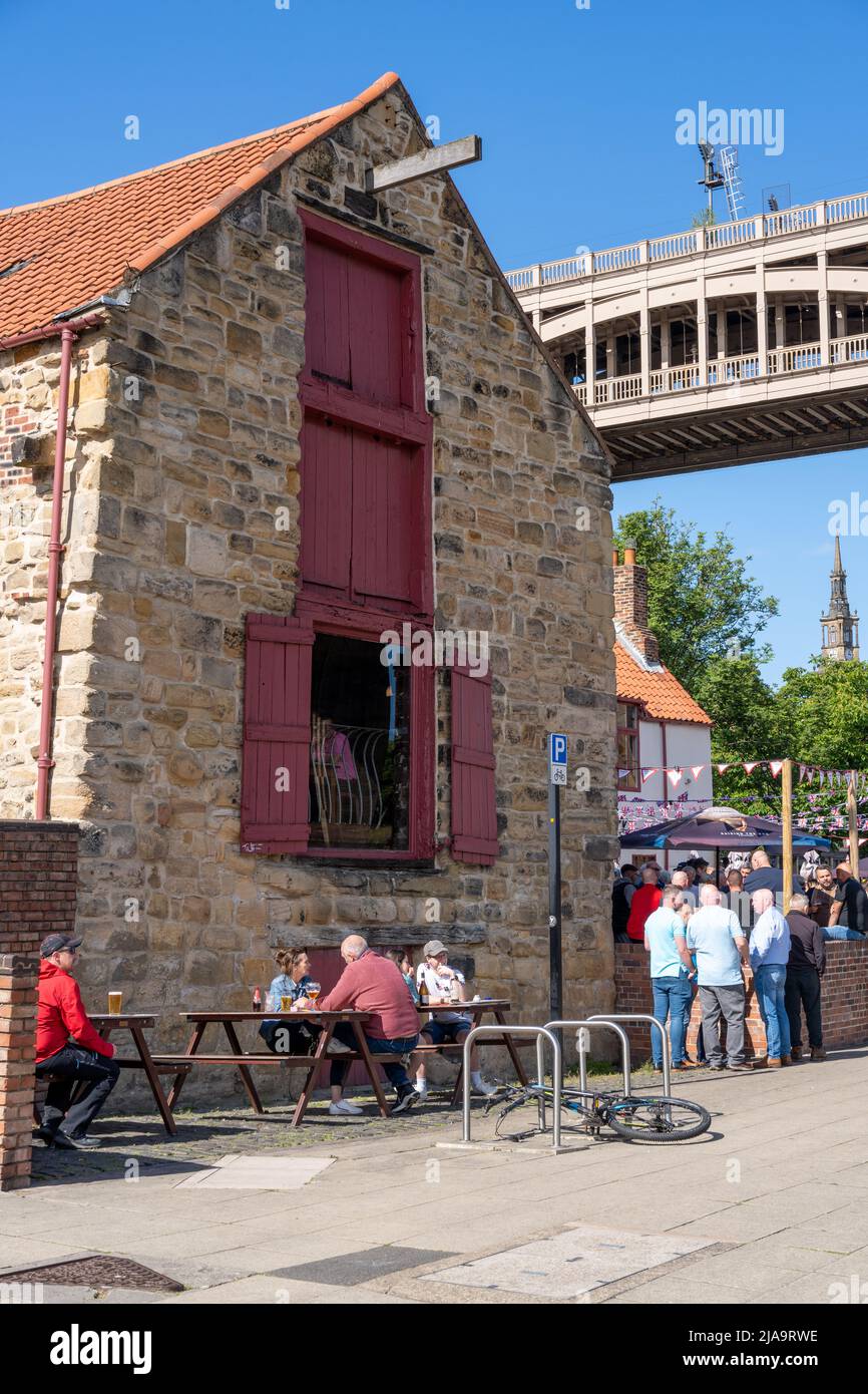 The traditional pub exterior and people drinking outside of the