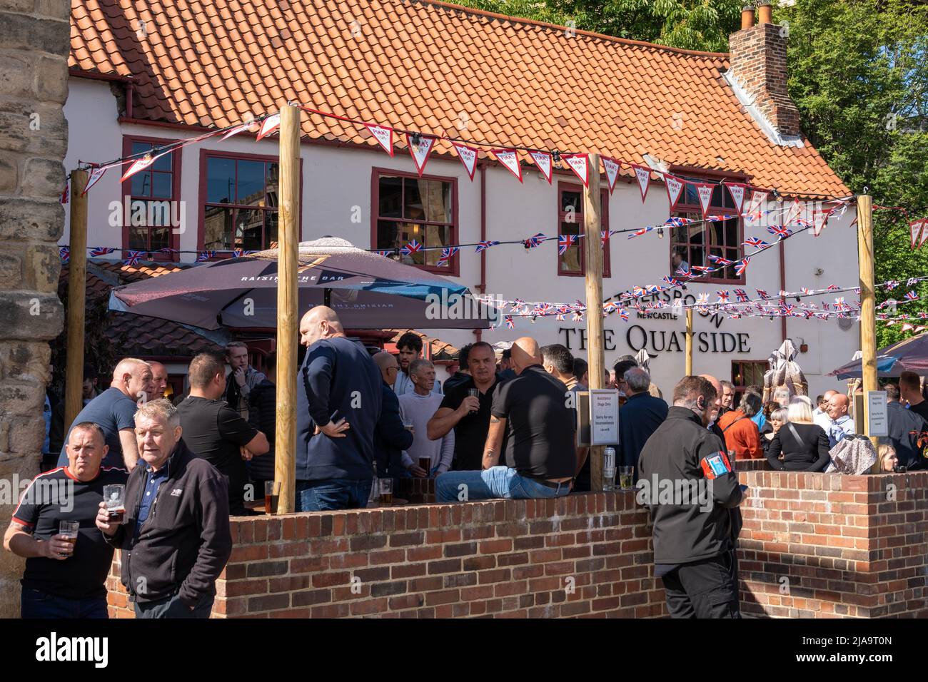 The traditional pub exterior and people drinking outside of the Wetherspoons Quayside Bar on a sunny day in Newcastle upon Tyne, UK. Stock Photo