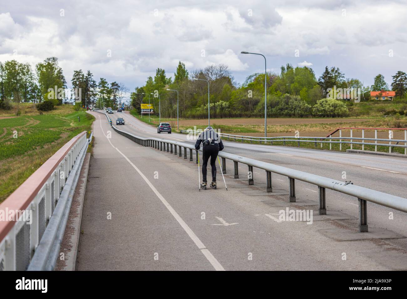 Man trains on roller skis on dedicated bike path on summer day. Sweden. Stock Photo