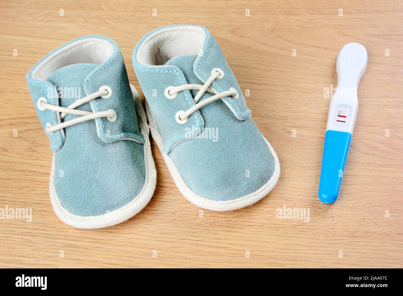Blue shoes with pregnancy test on a wooden table Stock Photo
