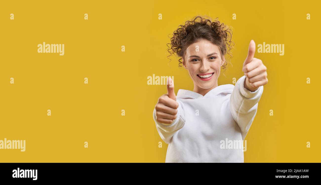 Young curly lady doing positive gesture with hands, approving indoors ...