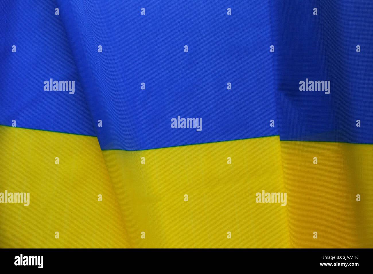 Close up shot of ruffled Ukrainian yellow and blue flag with a lot of copy space for text. Textured background. Stock Photo