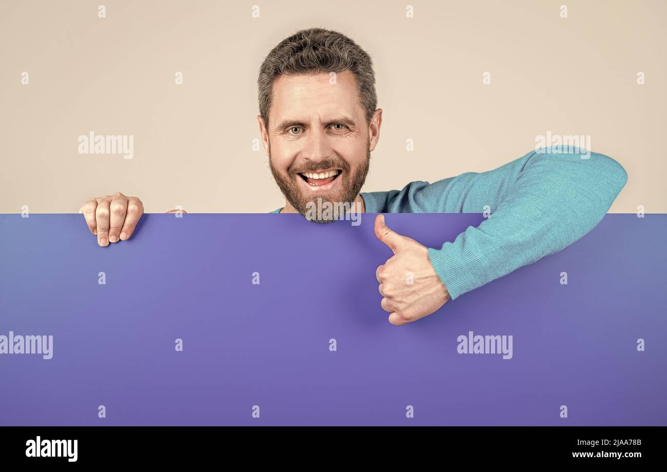 product presenting. presenting novelty information. male behind blue paper show thumb up. Stock Photo