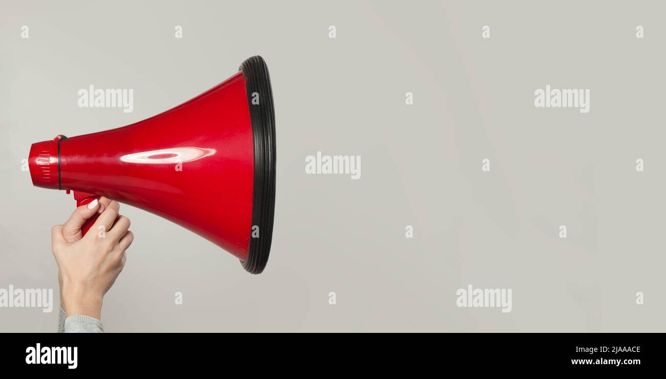 Hand holding red megaphone over white background Stock Photo - Alamy