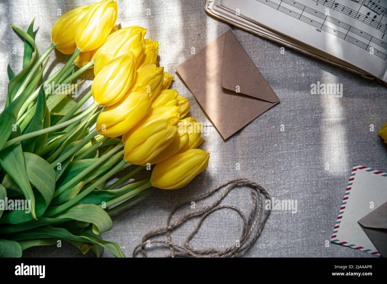 Flat lay, yellow tulips, envelopes and music notes. Stock Photo