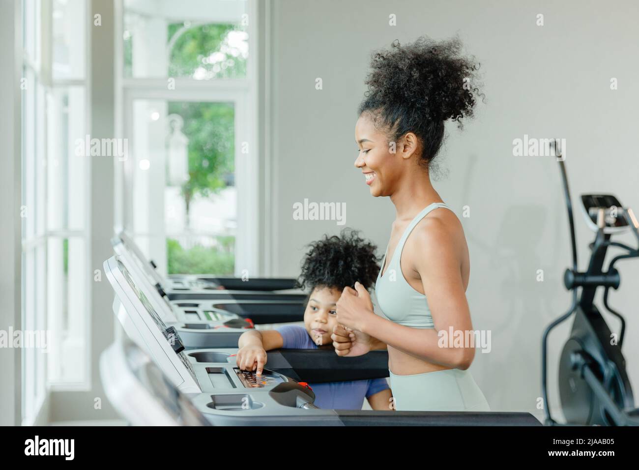 black girl teen sister running on treadmill happy smile with child. Stock Photo