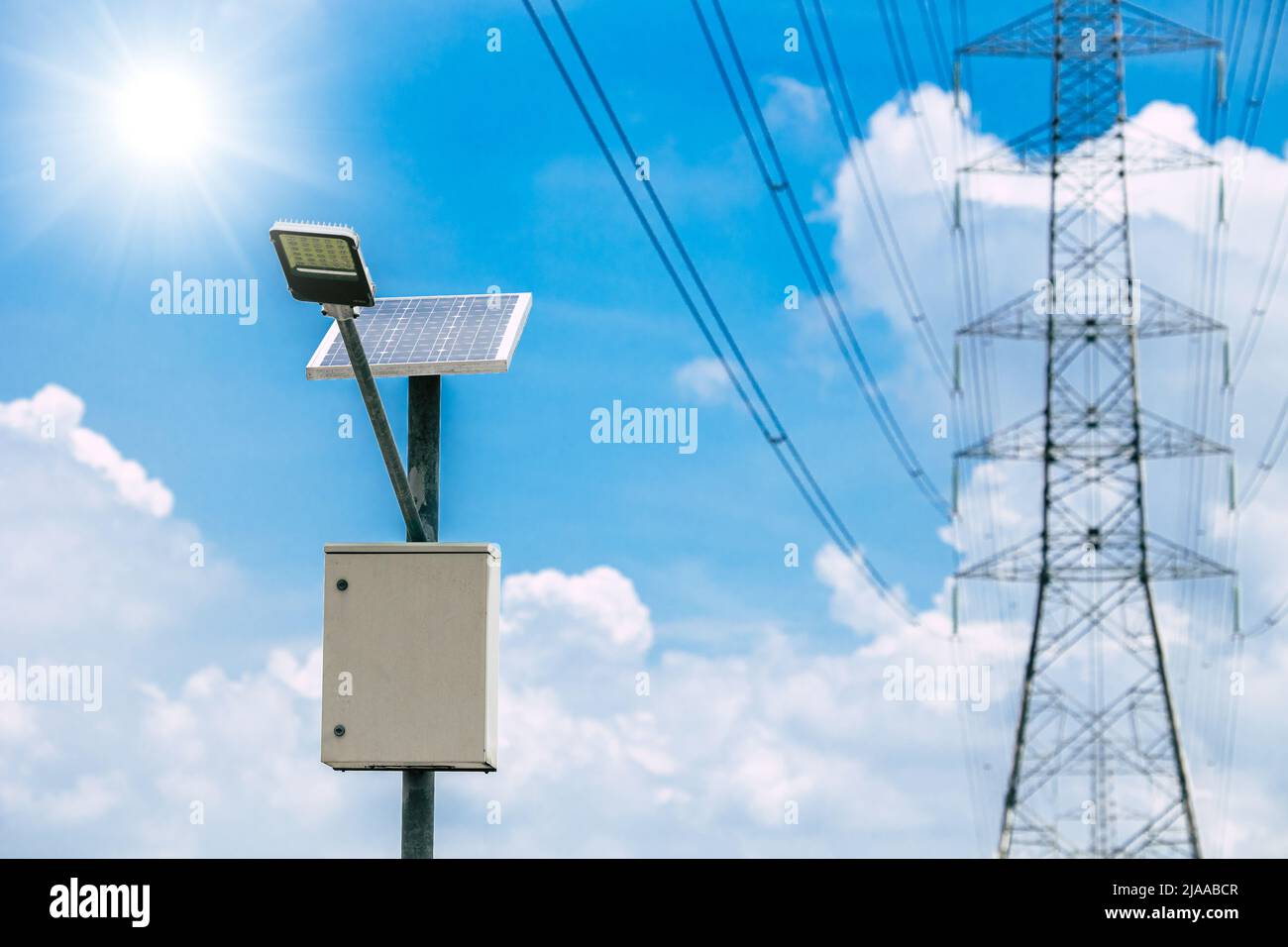 solar panel lamp with high voltage electricity tower on blue sky background for sustainable energy Stock Photo
