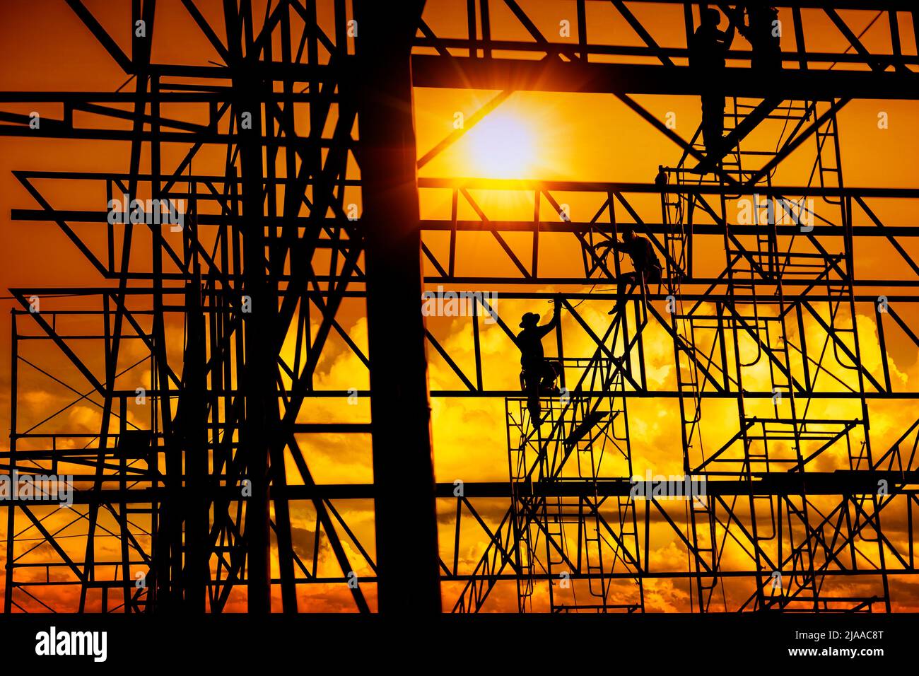 silhouette sunset of construction worker working in large metal structure of commercial building Stock Photo
