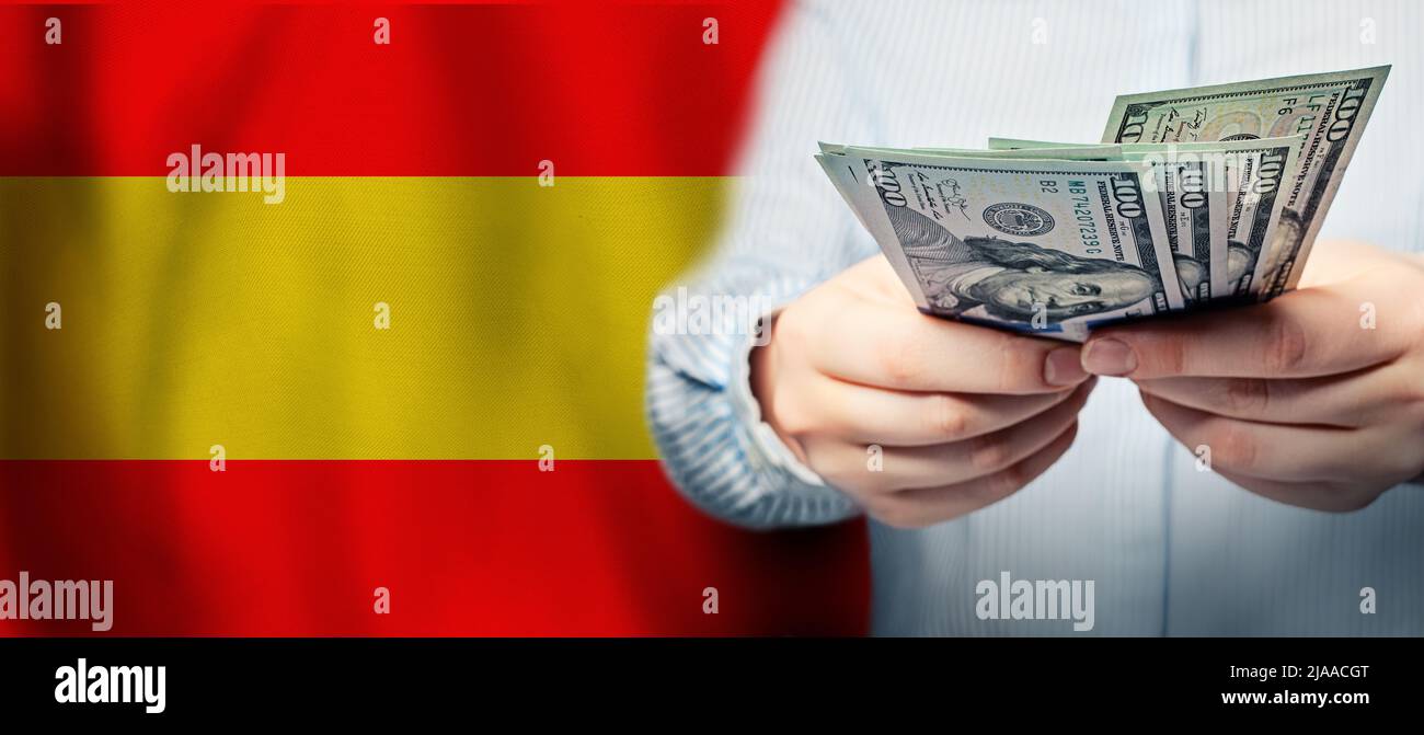 Hands holding us dollar bills on Spanish flag background. Currency