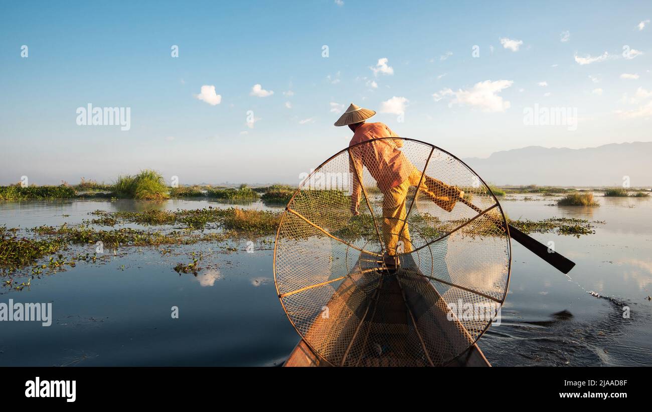 Intha fisherman leg rowing in traditional style at sunrise on Inle Lake, Shan State, Myanmar (Burma). Stock Photo