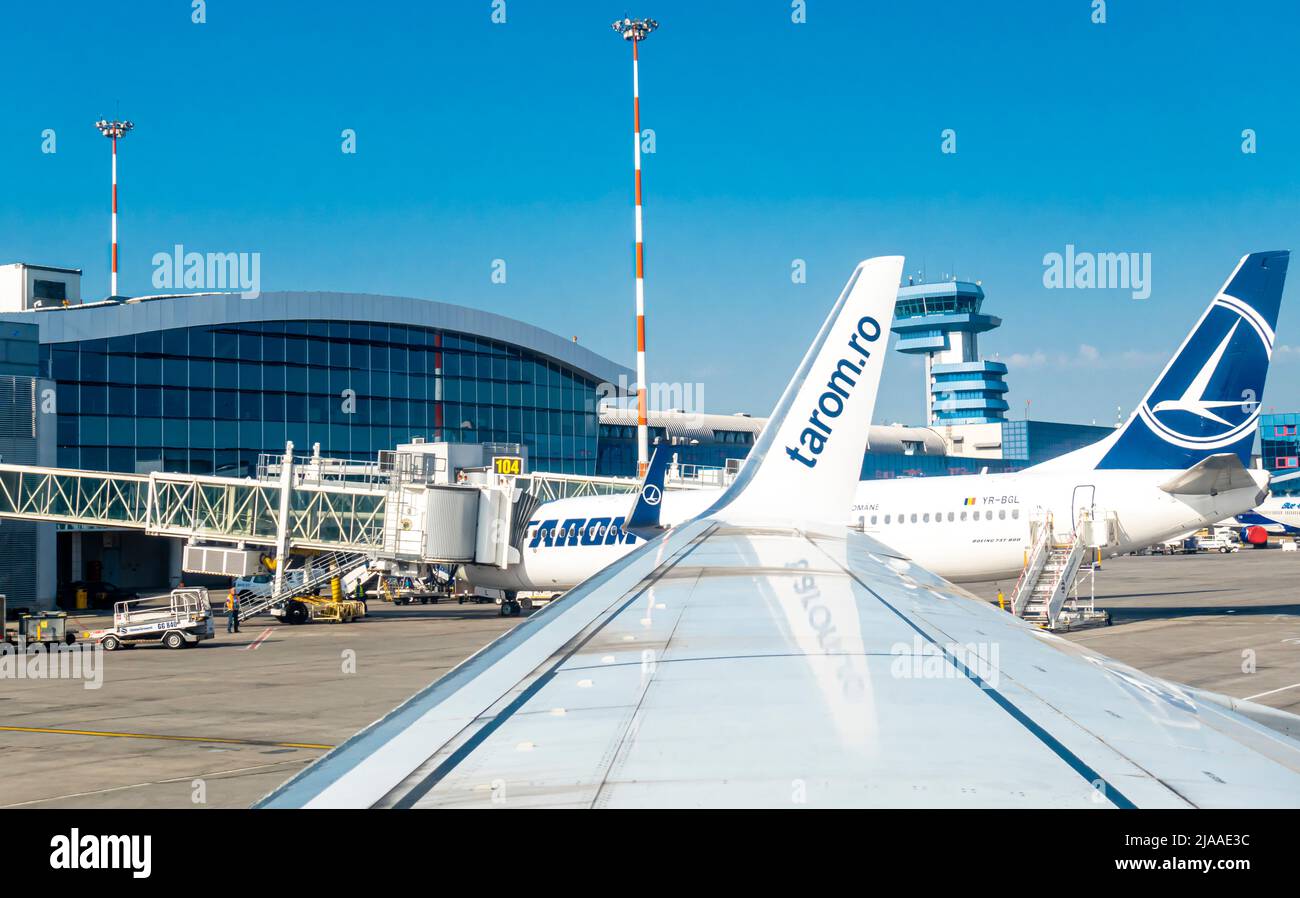 Bucharest Airport building, OTP, Otopeni, Romania with a control tower, tarom air carrier plane at gate. View from Tarom airplane window at wing side Stock Photo