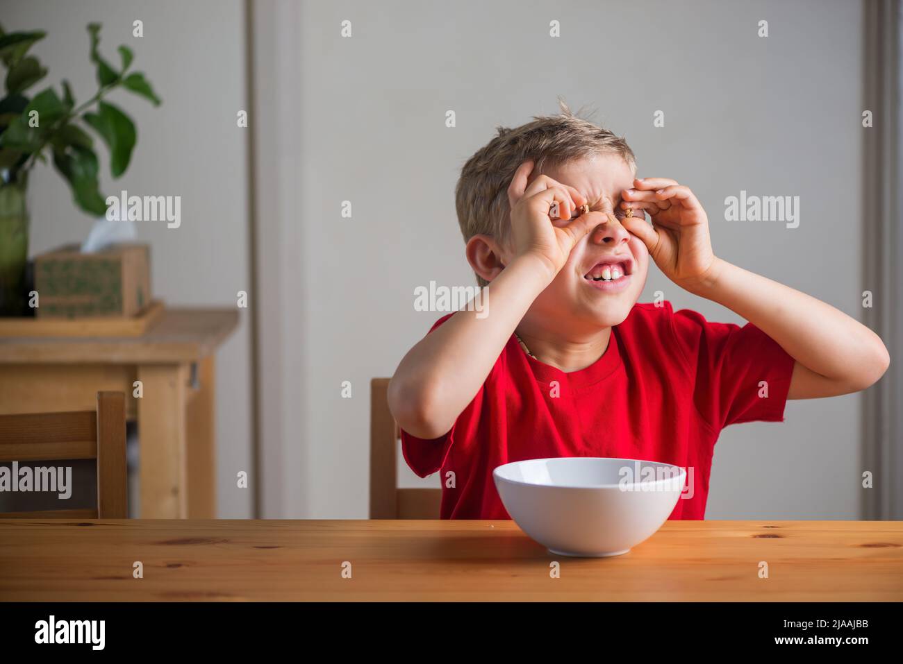 Cute boy playing with granola at breakfast. Genuine expressions Stock
