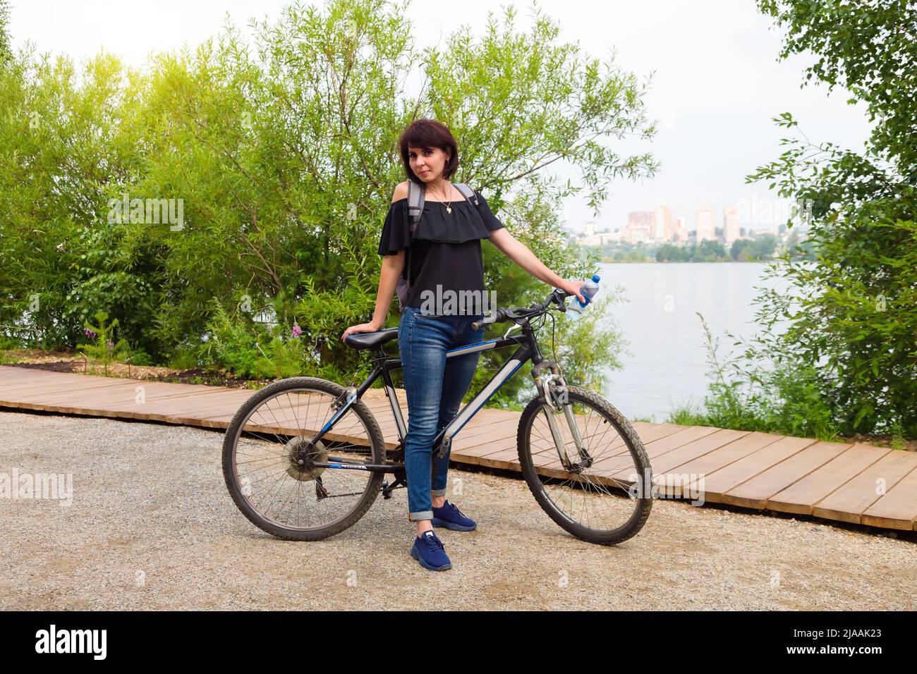 A happy female tourist with a backpack rides a bicycle park along the ...