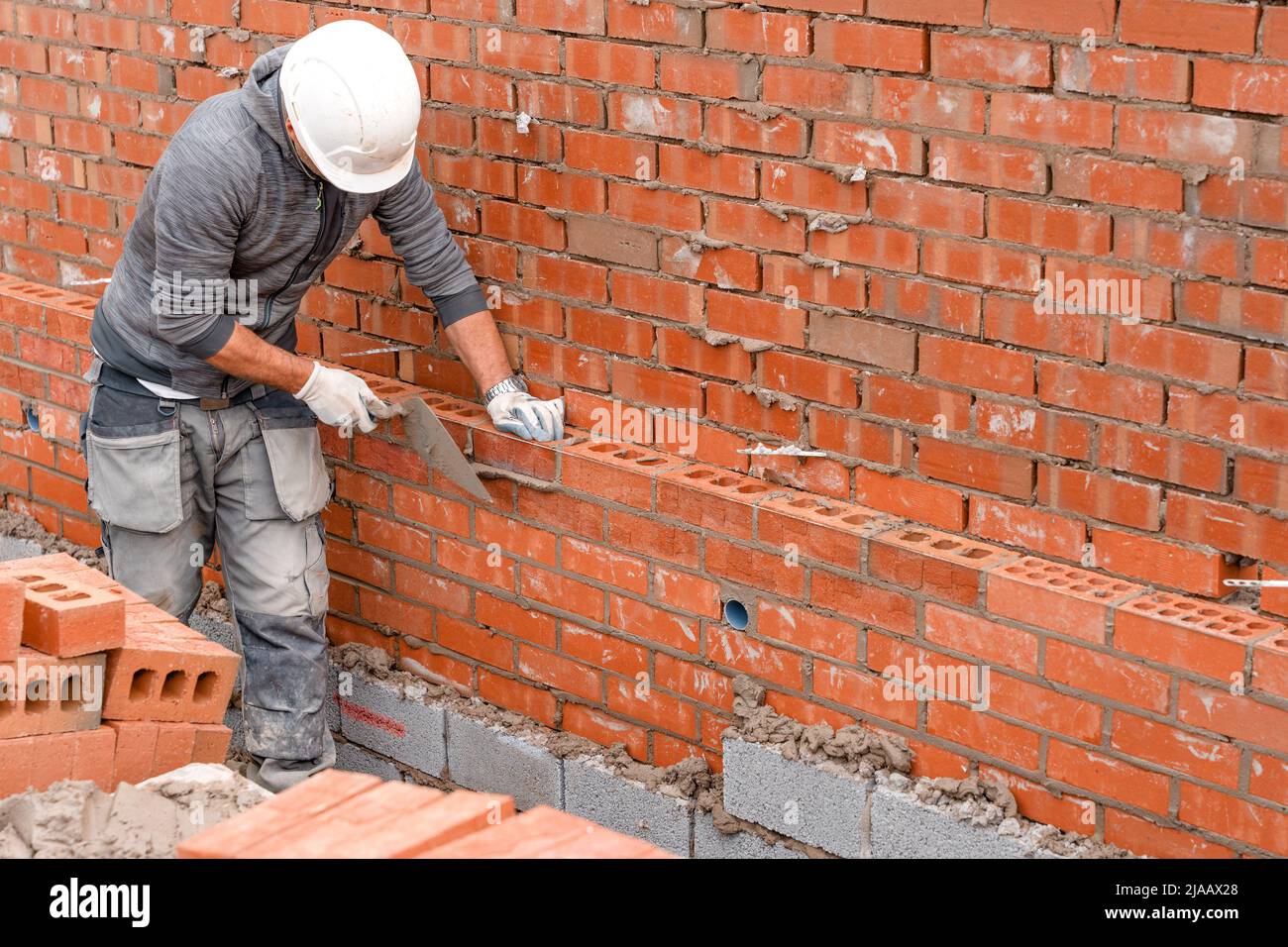 Bricklayer laying bricks on mortar on new residential house