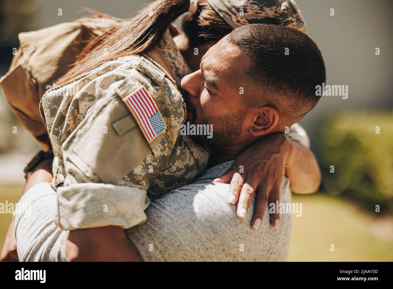 Heartwarming military homecoming. Female soldier embracing her husband after returning home from the army. American servicewoman reuniting with her hu Stock Photo