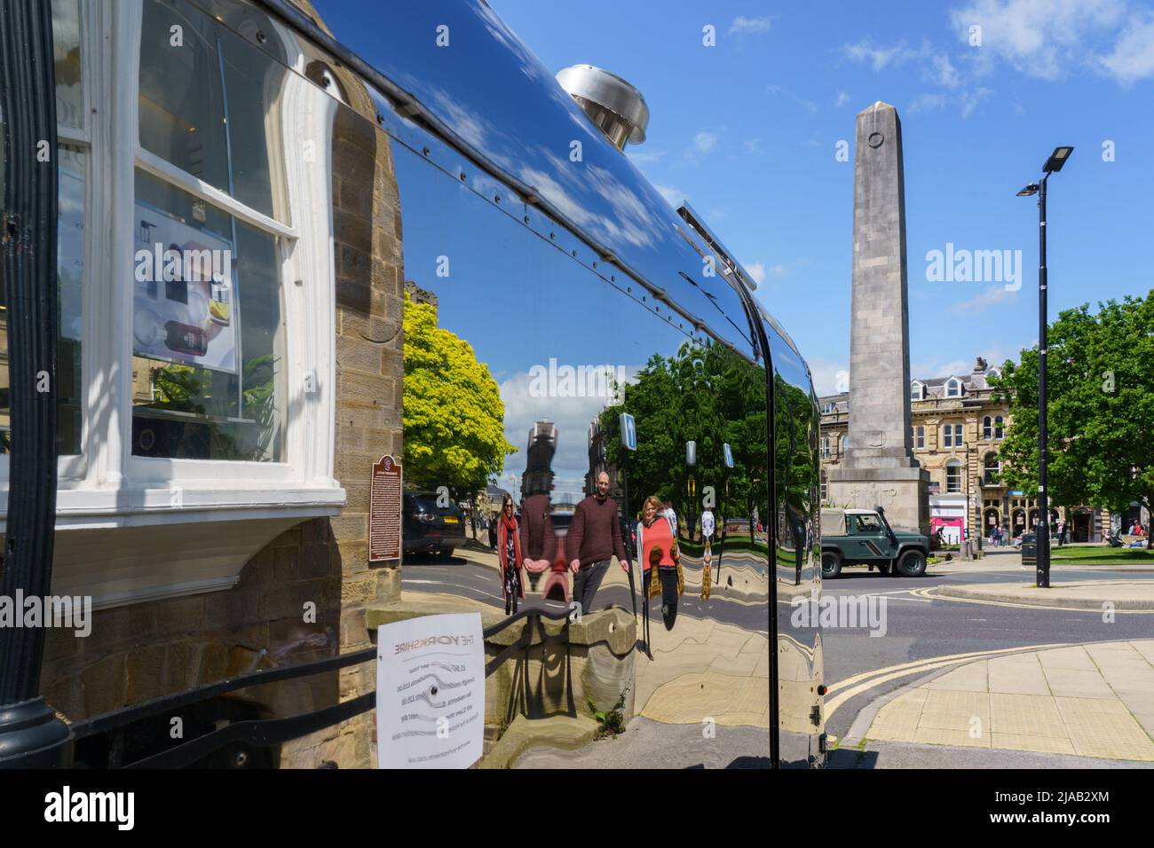 The Cenotaph War Memorial distorted reflection seen on the side of a shiny Airstream food truck stationary in Harrogate, North Yorkshire, England, UK. Stock Photo