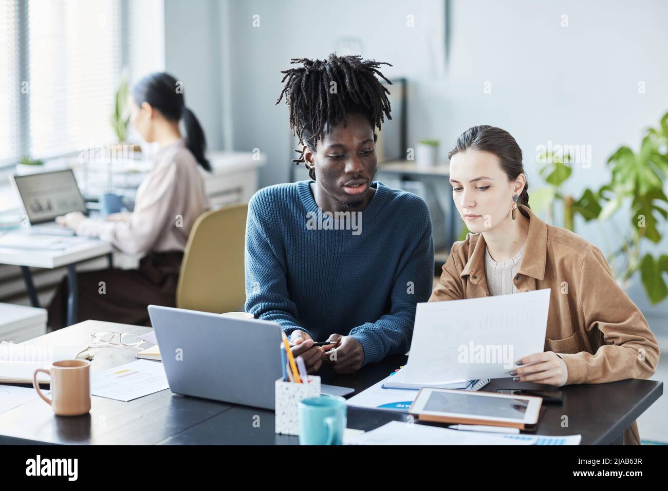 Portrait of two young business people using laptop during educational seminar in office Stock Photo