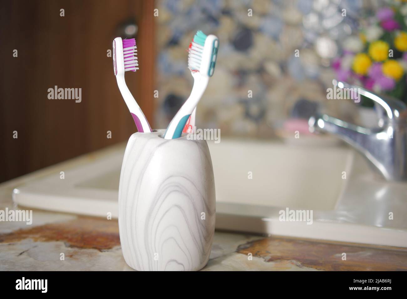 colorful toothbrushes in white mug against a wall Stock Photo - Alamy