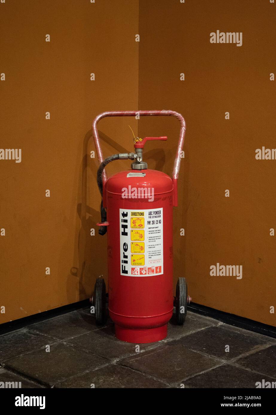 A fire extinguisher in the corner of the room is available in a fire emergency. Stock Photo