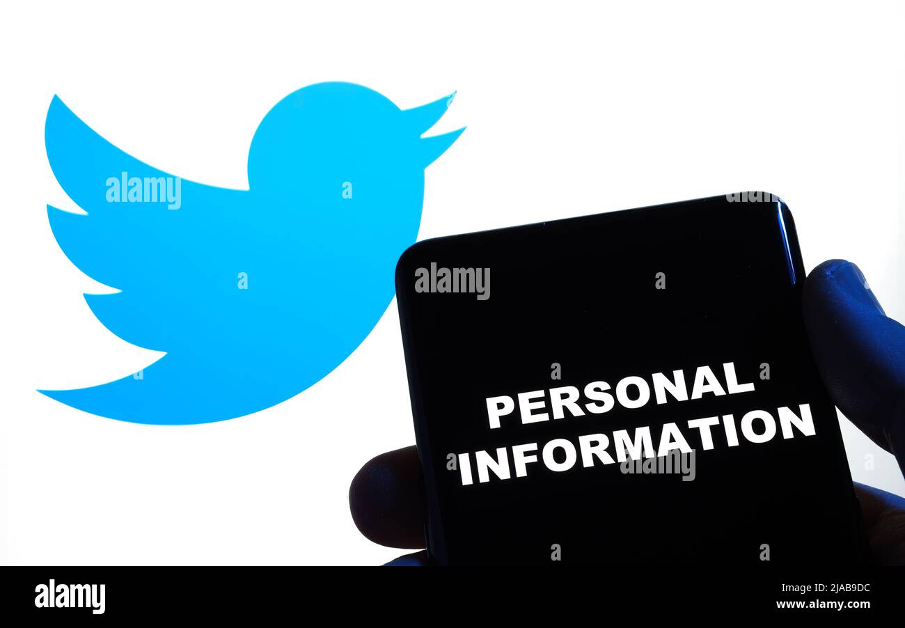 Words PERSONAL INFORMATION seen on smartphone and Twitter logo on blurred laptop behind it. Concept. Stafford, United Kingdom, May 29, 2022 Stock Photo