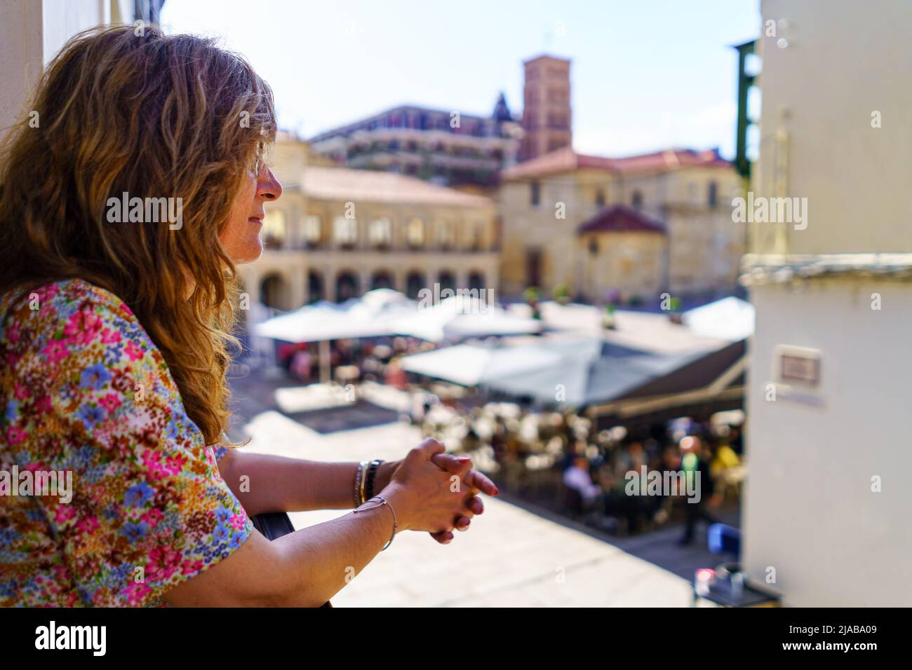 Mature white woman looking out onto the balcony and looking at the medieval city before her eyes. Stock Photo